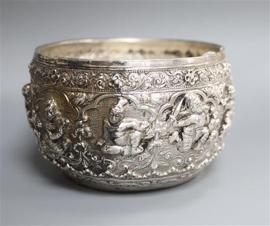 An early 20th century Burmese embossed white metal bowl, the base engraved with two seated figures, diameter approx. 13cm.